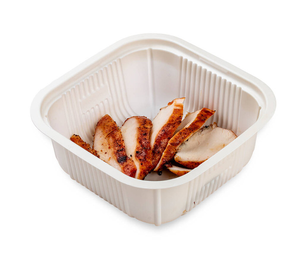 Grilled chicken breast cut into slices. In a plastic container. Food to go. On a light background. - Photo, Image