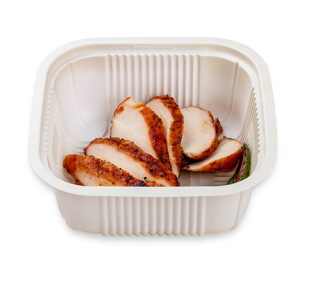 Grilled chicken breast cut into slices. In a plastic container. Food to go. On a light background. - Photo, Image