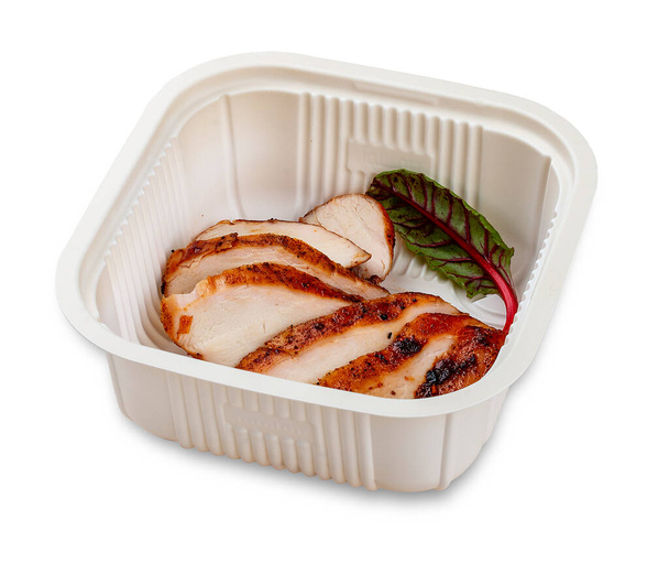 Grilled chicken breast cut into slices. In a plastic container. Food to go. On a light background. - Fotó, kép