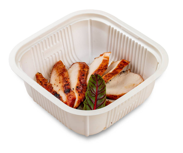 Grilled chicken breast cut into slices. In a plastic container. Food to go. On a light background. - Photo, image
