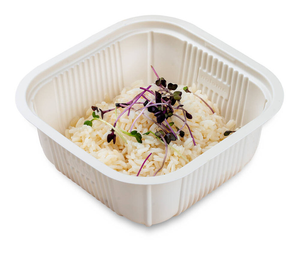 Boiled white rice with micro grits. Garnish. In a plastic container. Food to go. On a light background. - Foto, Imagen