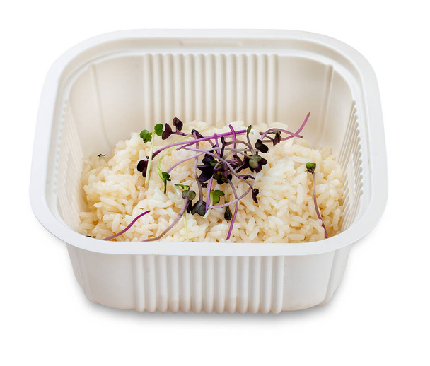 Boiled white rice with micro grits. Garnish. In a plastic container. Food to go. On a light background. - Foto, Imagen