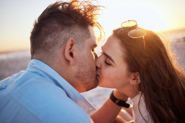 Kissing, couple love and sunset beach bonding, relax and break on summer vacation together outdoors. Man, woman and young people face in loving relationship, honeymoon date and romance sea holiday. - Fotografie, Obrázek