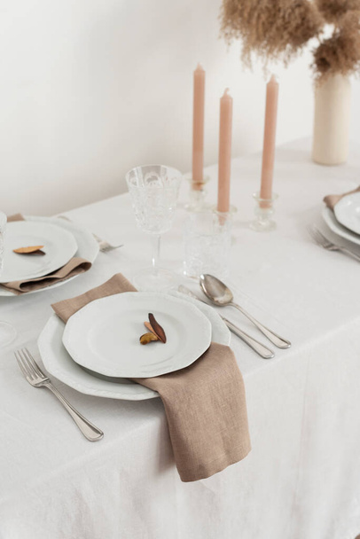 Concept of table decoration with linen white tablecloth and beige napkins, selective focus image - Foto, immagini