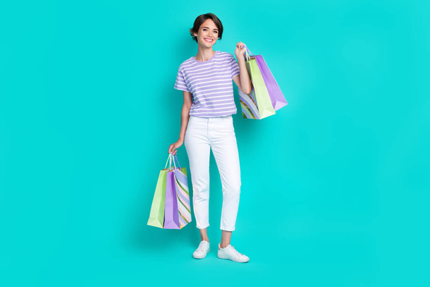 Full length photo of pretty adorable girl dressed purple t-shirt smiling rising bargains isolated teal color background. - Fotó, kép