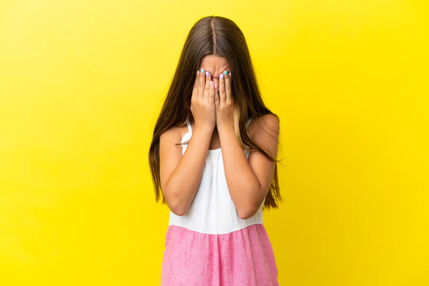 Little caucasian girl isolated on yellow background with tired and sick expression - Фото, изображение