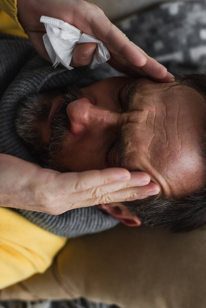 bovenaanzicht van zieke man met gesloten ogen die lijden aan migraine en ontroerende kop - Foto, afbeelding