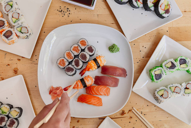 Fecha as mãos tomando um pedaço de sushi com pauzinhos. Frutos do mar saudáveis e pratos asiáticos japoneses. - Foto, Imagem