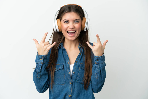 Giovane donna caucasica isolata su sfondo bianco ascoltare musica fare gesto rock - Foto, immagini