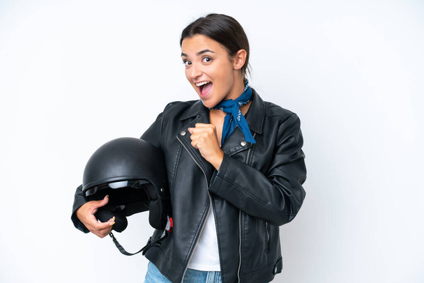 Mavi arka planda izole edilmiş motosiklet kasklı beyaz bir kadın zaferi kutluyor. - Fotoğraf, Görsel