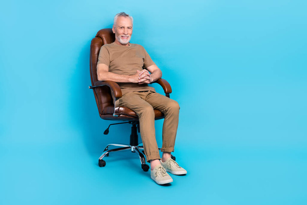 Full length photo of satisfied aged man sitting leather chair isolated on blue color background. - Фото, зображення