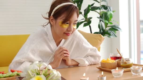 Mooie Aziatische vrouw doet spa thuis Ze maskeerde haar gezicht met gouden zijden kruiden. Stimuleert de huid om glad en mooi te zijn. schoonheidsconcept - Video