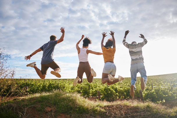 Vrienden, natuur en het springen voor vrijheid op het platteland voor zomervakantie samen in de buitenlucht. Groep van vrije mensen genieten van vakantie of reizen in vreugdevol plezier buiten in Zuid-Afrika. - Foto, afbeelding