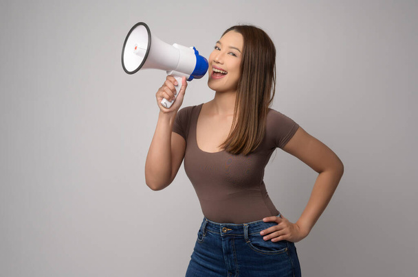 A Young smiling woman holding megaphone over white background studio.	 - 写真・画像