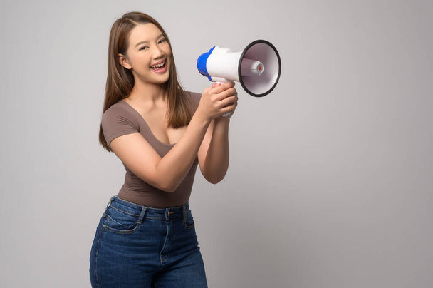 A Young smiling woman holding megaphone over white background studio.	 - Foto, Bild