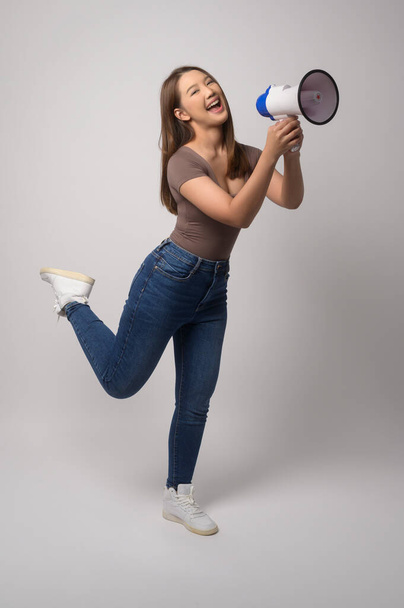 A Young smiling woman holding megaphone over white background studio.	 - Fotoğraf, Görsel