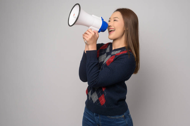 A Young smiling woman holding megaphone over white background studio.	 - 写真・画像