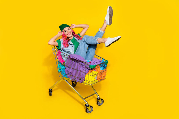 Full length photo of sweet pretty lady wear jeans waistcoat riding tray volunteer help clothes stack isolated yellow color background. - 写真・画像