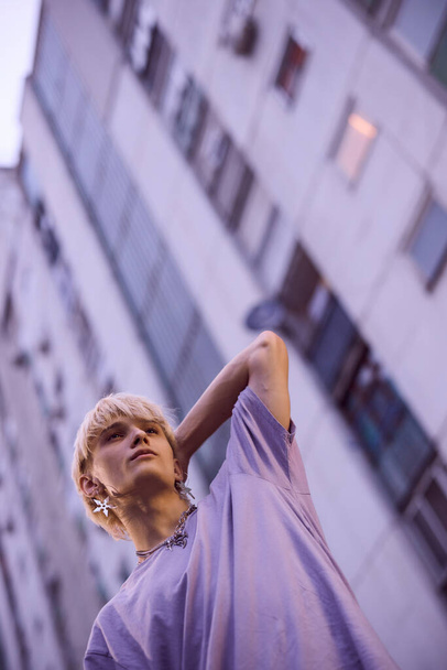 Un adolescente posa en el exterior urbano rodeado de edificios. - Foto, Imagen