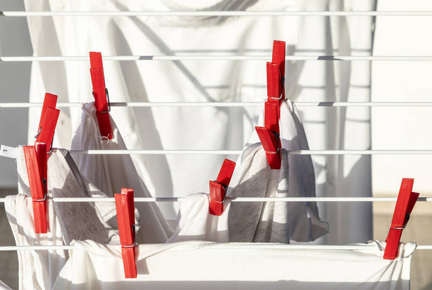 chemise blanche séchant au soleil avec des épingles à linge rouges en détail - Photo, image