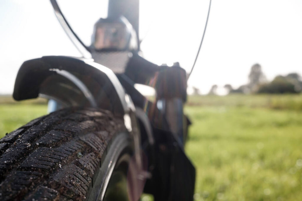 Bike tire on a bicycle wheel against the background of a field in the countryside, on a summer day. Close-up. - Photo, Image