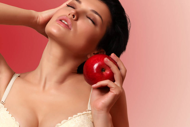 sexy dziewczyna z dużym biustem w biustonosz z czerwonym jabłkiem w dłoni - Zdjęcie, obraz