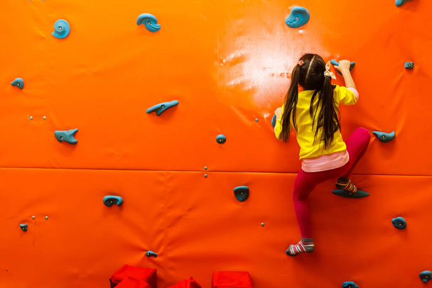Mädchen klettert auf Spielplatz auf Mauer - Foto, Bild