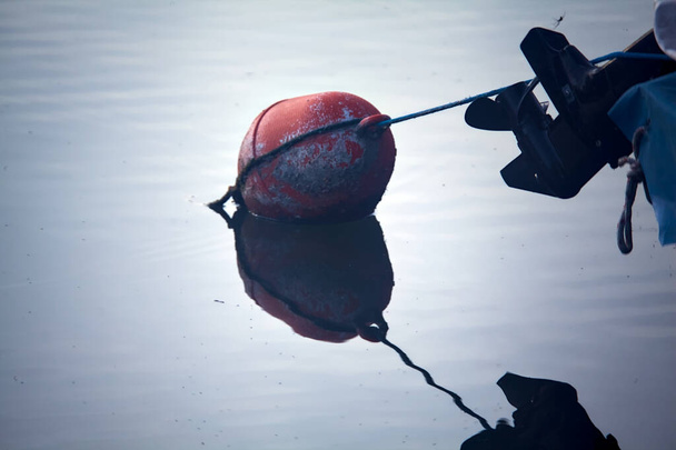 Boya flotando en el agua y su reflejo fundido debajo de ella - Foto, Imagen