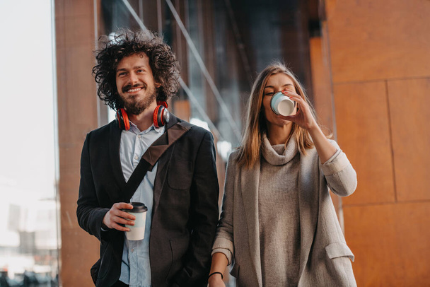 Businessmen and businesswomen talking and holding luggage traveling on a business trip, carrying fresh coffee in their hands. Business concept. High quality photo - Foto, Imagem