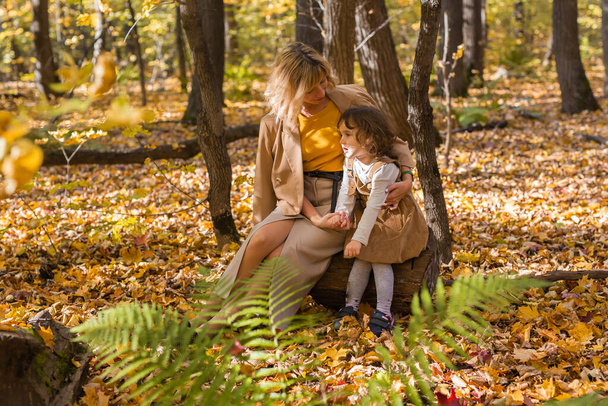 Beautiful lifestyle autumn photo mother and child walks evening in the park, warm sunlight - Photo, Image