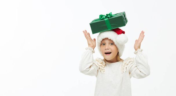 Christmas child. Cute toddler girl  in santa claus caps holding colorful gift boxes on white. Wow fanny face. Preparing for New Year's holidays in Italy - Foto, Bild