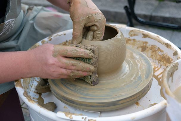 Close-up handen werken op aardewerk wiel en het maken van een klei pot, selectieve focus - Foto, afbeelding