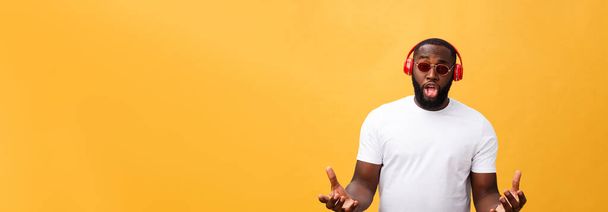 Jovem afro-americano vestindo fone de ouvido e desfrutar de música sobre ouro amarelo Fundo
. - Foto, Imagem