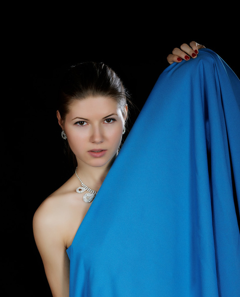 Portrait of the girl  wrapped up dark blue fabric on a black bac - Fotografie, Obrázek