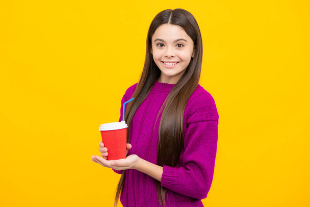 Nastolatka trzymająca filiżankę gorącej kawy lub herbaty. Dziecko z kubkiem na wynos na żółtym tle, napój energetyczny rano - Zdjęcie, obraz