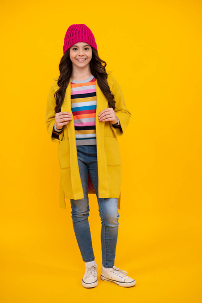 Pełna długość wesoły nastolatek dziewczynka nosi wygodne modny płaszcz jesienny moda, izolowane na żółtym tle. Szczęśliwy nastolatek, pozytywne i uśmiechnięte emocje nastolatki - Zdjęcie, obraz