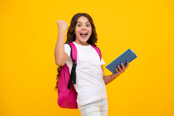 Amazed teen girl. Back to school. Teenager school girl hold book and copybook ready to learn. School children with school bag on isolated yellow studio background. Excited expression, cheerful and - Photo, Image