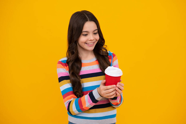 Teenager dítě s šálkem kávy izolované na žlutém pozadí studia. Holka, co pije, bere pití. Šťastný teenager, pozitivní a usměvavé emoce dospívající dívky - Fotografie, Obrázek