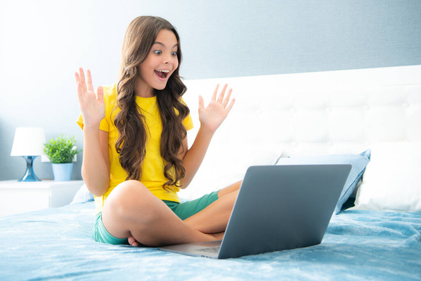 Happy teen teenage girl on bed at home using laptop. Child browse internet on computer, friendship communication - Φωτογραφία, εικόνα
