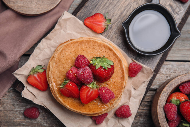 Tasty pancakes served with honey and berries on wooden table, flat lay - Foto, Bild