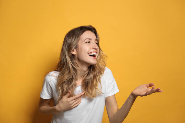 Cheerful young woman laughing on yellow background - Foto, imagen