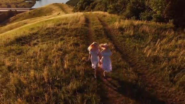Két fiatal szőke nő nyári fényben felszalad a dombra. Légi felvétel - Felvétel, videó