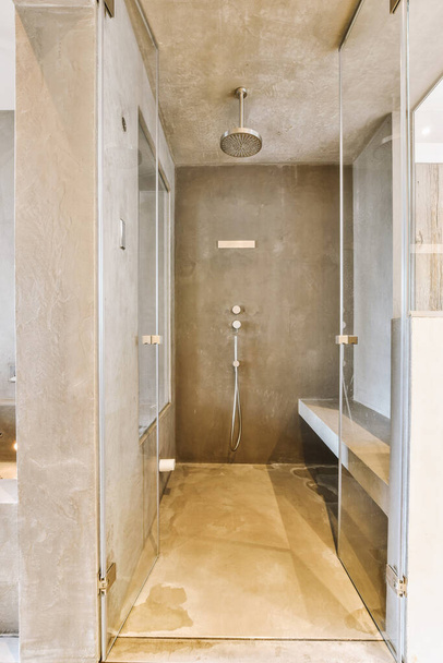 Інтер'єр сучасної ванної кімнати з душем і мармуровими стінами в мінімальному стилі
 - Фото, зображення