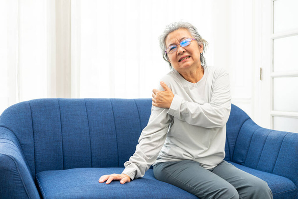 Seniorin leidet zu Hause an Schulterschmerzen. Unzufriedene Frau mittleren Alters leidet unter Schulterschmerzen - Foto, Bild