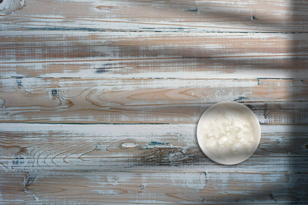 Pohled shora na bílou máslovou smetanu na bílé misce nad dřevěným stolem. přidán prostor pro kopírování textu. - Fotografie, Obrázek