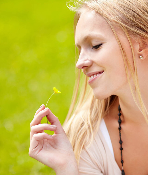 Feeling carefree. Cute young woman looking at a flower while outdoors - Foto, Bild
