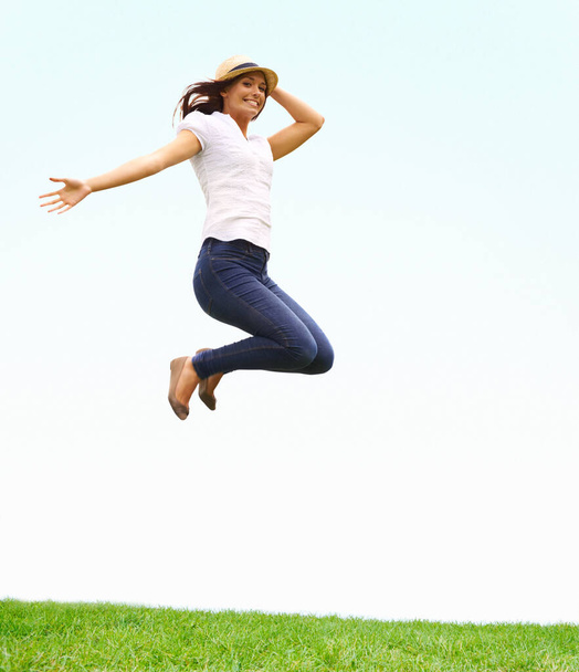 I feel great. Young woman leaping with joy while holding on to her hat - Foto, imagen