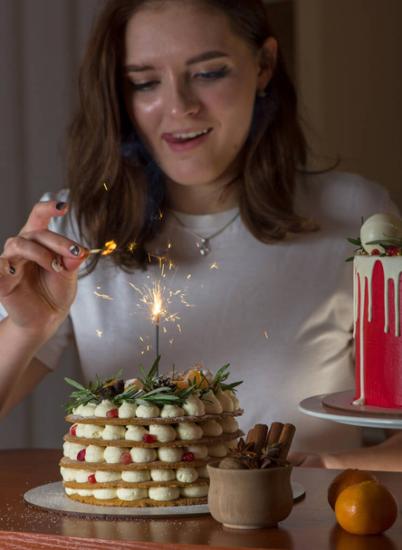 Young blonde girl in her kitchen holding a Christmas cake enjoying the smell - Photo, Image