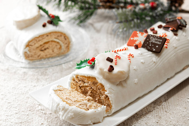 Weiße Schokolade yule log cake mit Ornament auf Holztisch - Foto, Bild