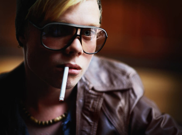 Заводите плохие привычки. Молодой парень в городской одежде с сигаретой, свисающей с его губ - Фото, изображение